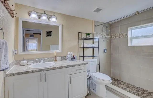 a bathroom with a granite countertop sink a toilet and a mirror