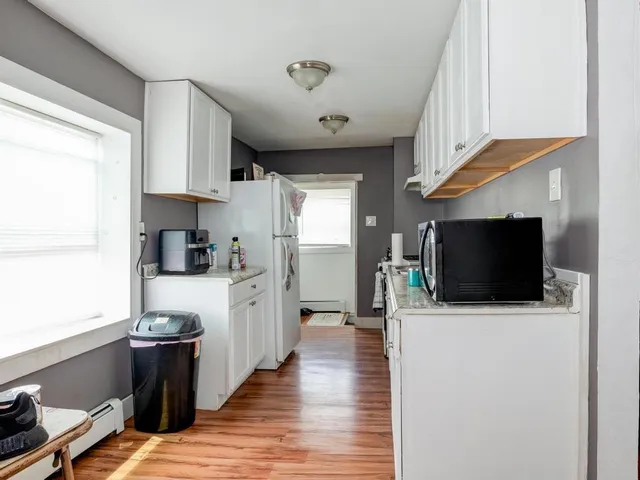 a kitchen with stainless steel appliances kitchen island granite countertop a refrigerator a sink a stove and white cabinets