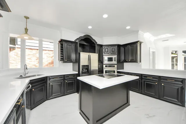 a kitchen with stainless steel appliances granite countertop a sink a stove and refrigerator