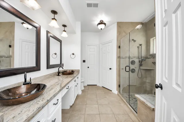 a bathroom with a granite countertop sink a mirror and a shower