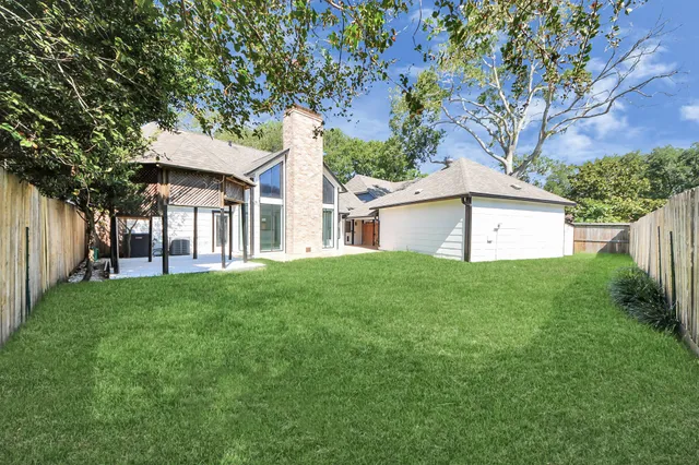 a view of a house with a yard and a large tree