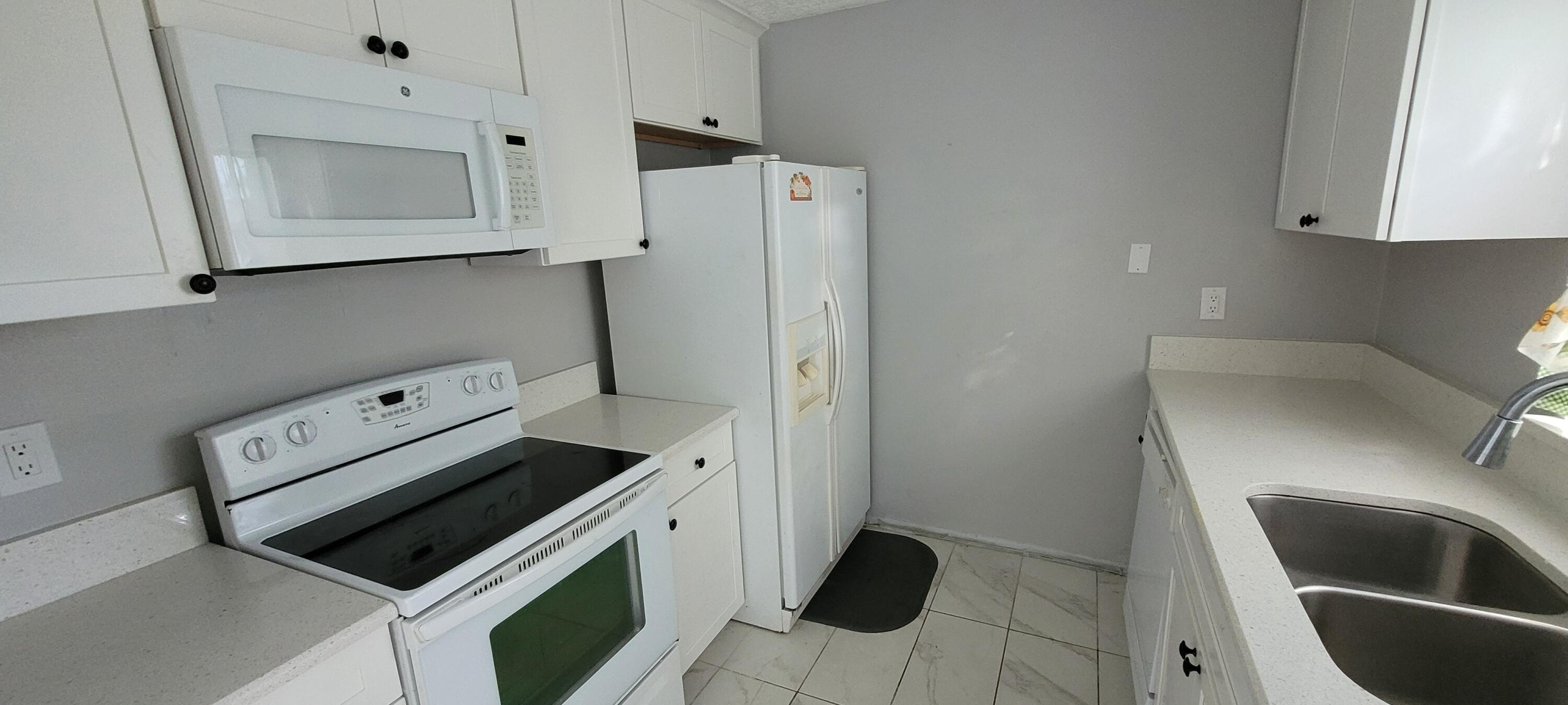 351 West 21st Street Riviera Beach, FL 33404 - Photo 4 of 11 a kitchen with stainless steel appliances a stove a microwave and a refrigerator