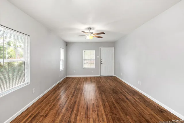 an empty room with wooden floor and windows
