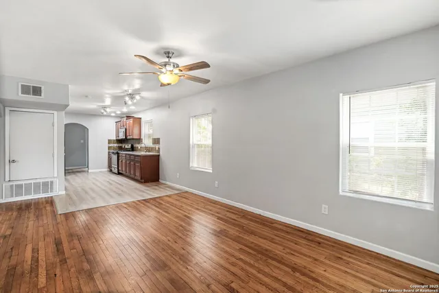 a view of an empty room with window and wooden floor