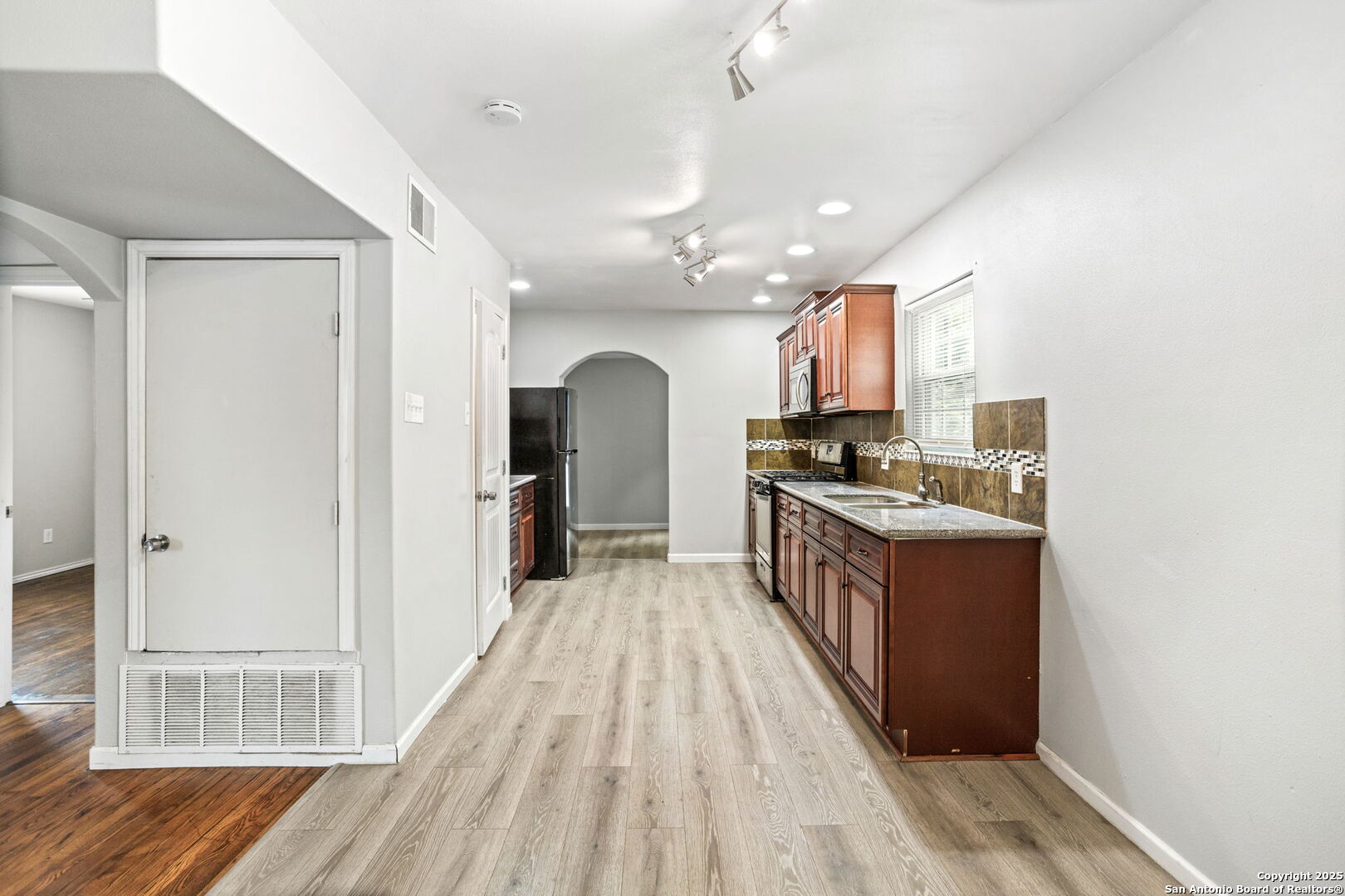 1336 West Ridgewood Court, Unit 1 San Antonio, TX 78201 - Photo 6 of 15 a kitchen with stainless steel appliances granite countertop a refrigerator a sink dishwasher a stove and white cabinets with wooden floor