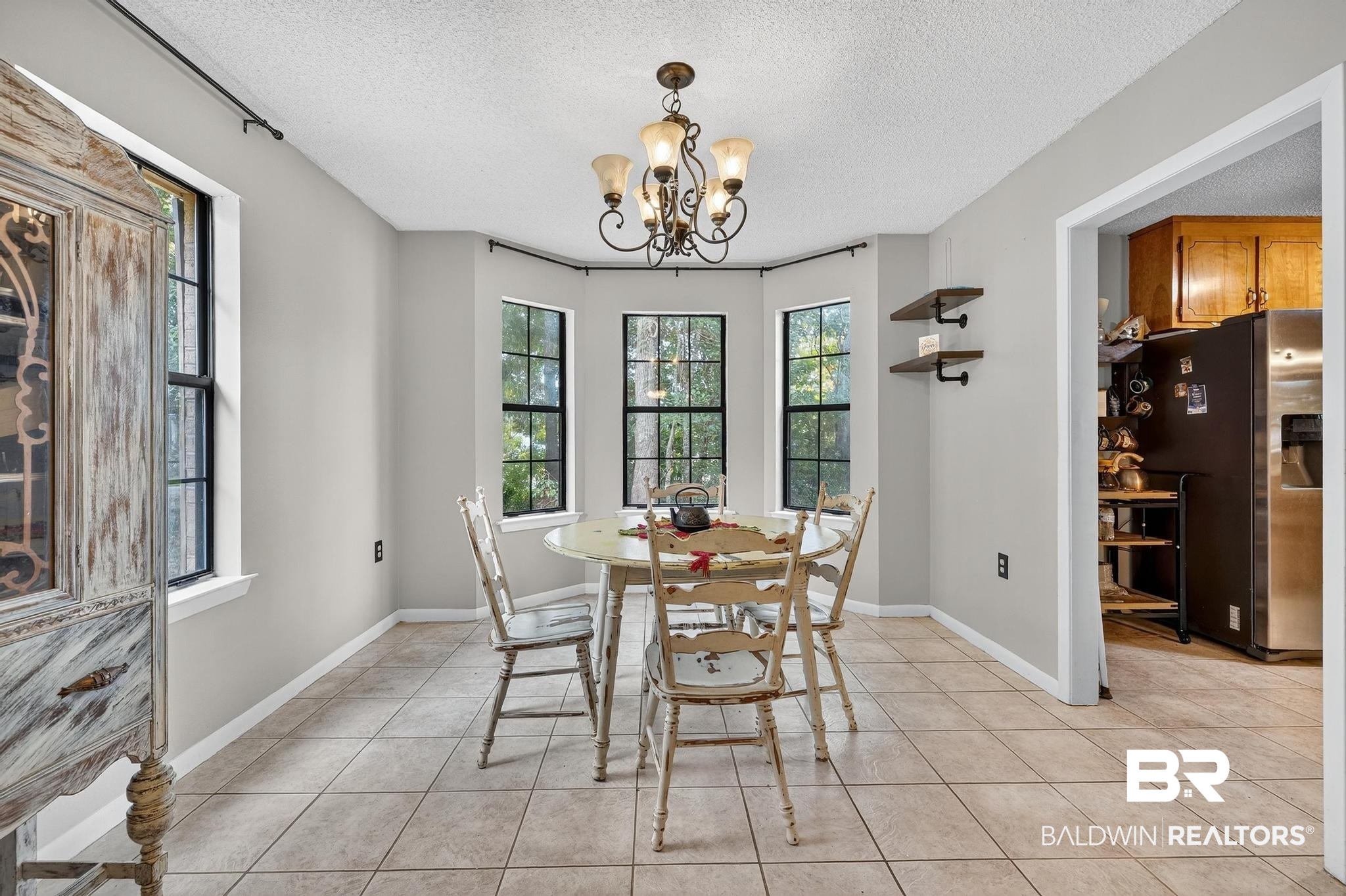 21895 2nd Street Silverhill, AL 36576 - Photo 25 of 43 Dining room featuring light tile floors, a bay window, and a chandelier