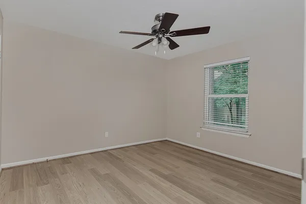 a view of empty room with wooden floor and fan