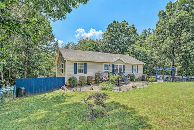 a front view of a house with garden and trees