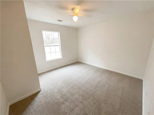 an empty room with windows and fan