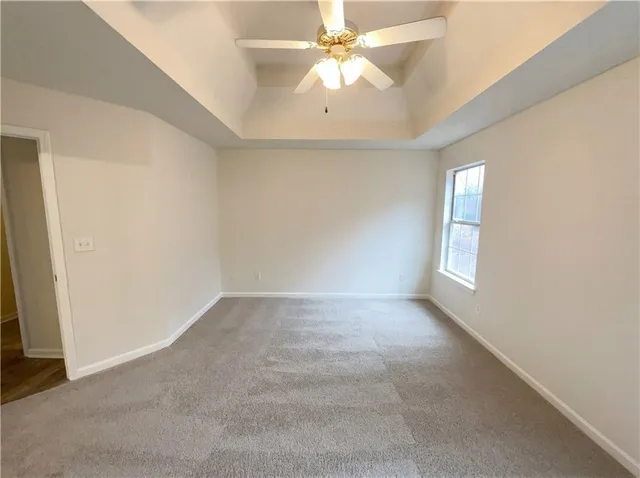 an empty room with a chandelier fan and windows
