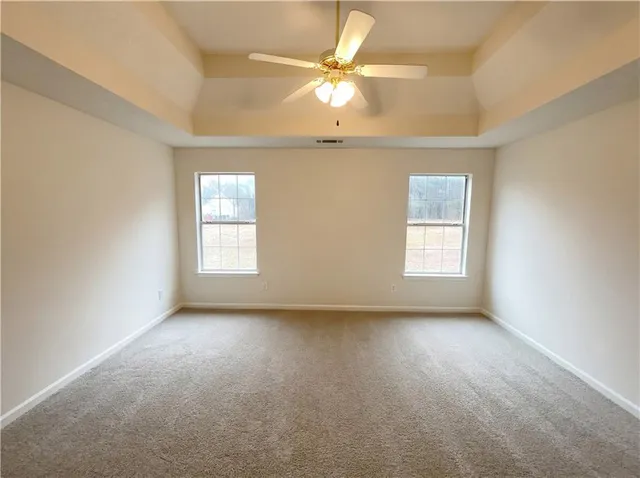 an empty room with a window and a ceiling fan