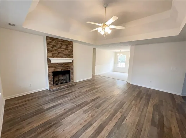 an empty room with wooden floor fireplace and windows