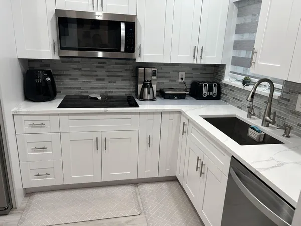 a kitchen with white cabinets and black appliances