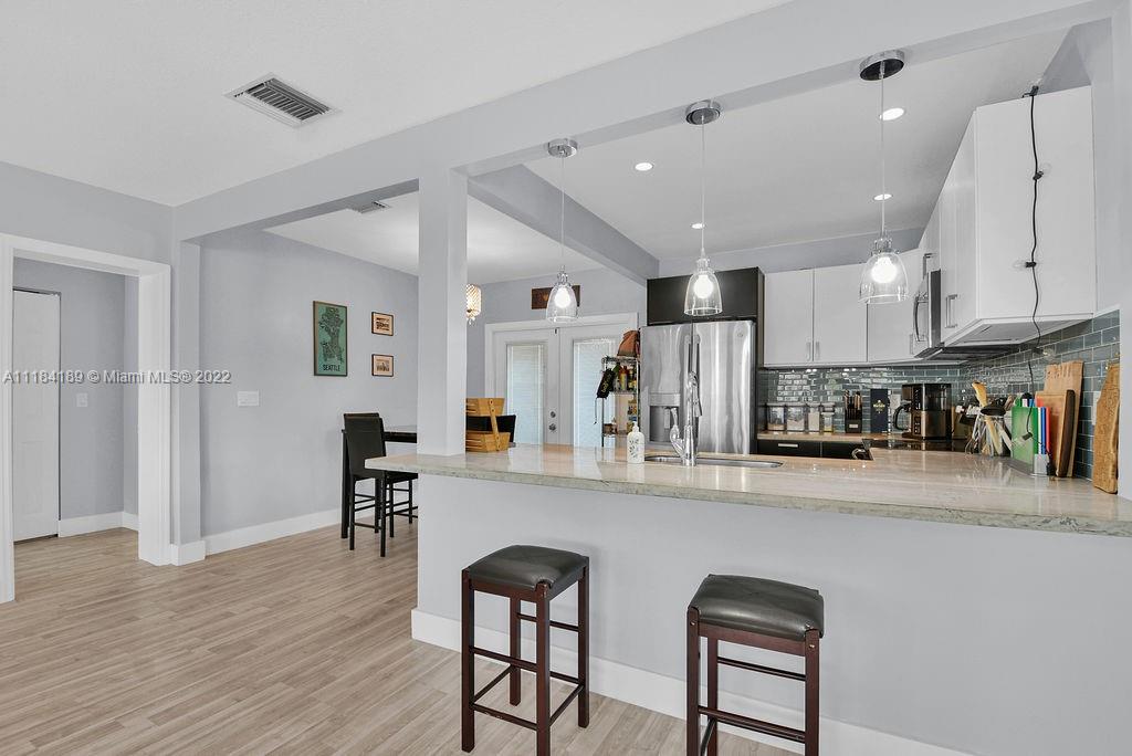 331 Northwest 144th Street Miami, FL 33168 - Photo 17 of 35 a kitchen with stainless steel appliances kitchen island granite countertop a refrigerator a stove a sink a dining table and chairs with wooden floor