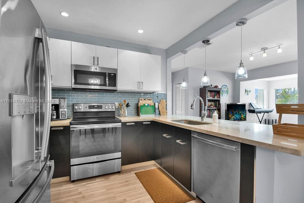 331 Northwest 144th Street Miami, FL 33168 - Photo 22 of 35 a kitchen with stainless steel appliances a sink a stove top oven a refrigerator and a center island