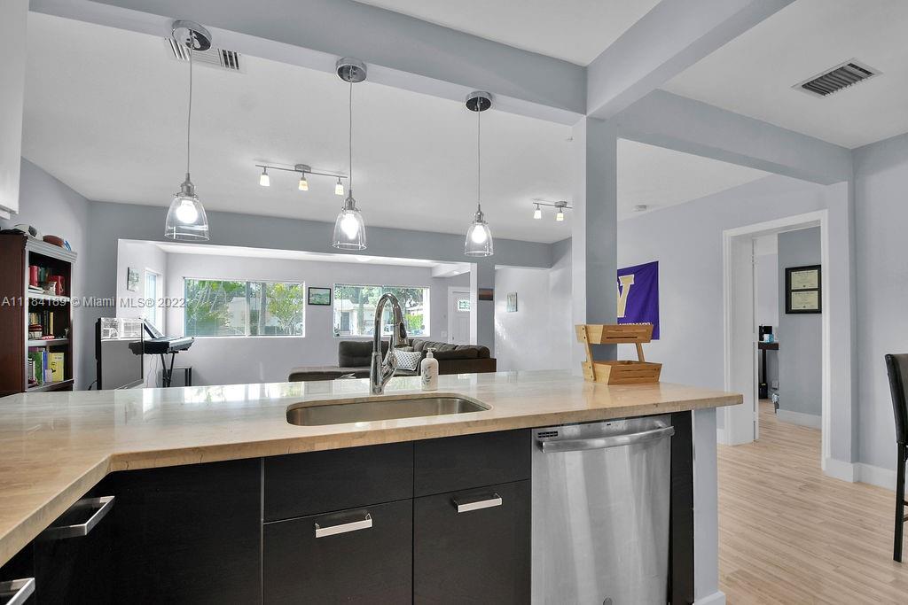 331 Northwest 144th Street Miami, FL 33168 - Photo 23 of 35 a kitchen with stainless steel appliances kitchen island granite countertop a sink cabinets and wooden floor