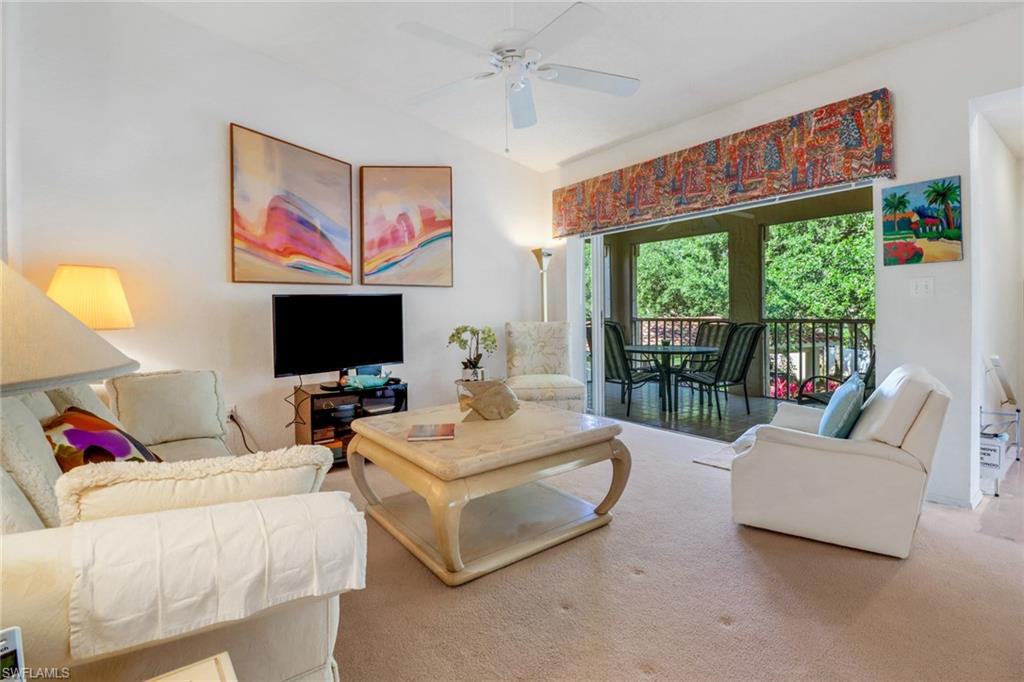 110 Siena Way, Unit 206 Naples, FL 34119 - Photo 5 of 35 a living room with furniture a flat screen tv and a floor to ceiling window