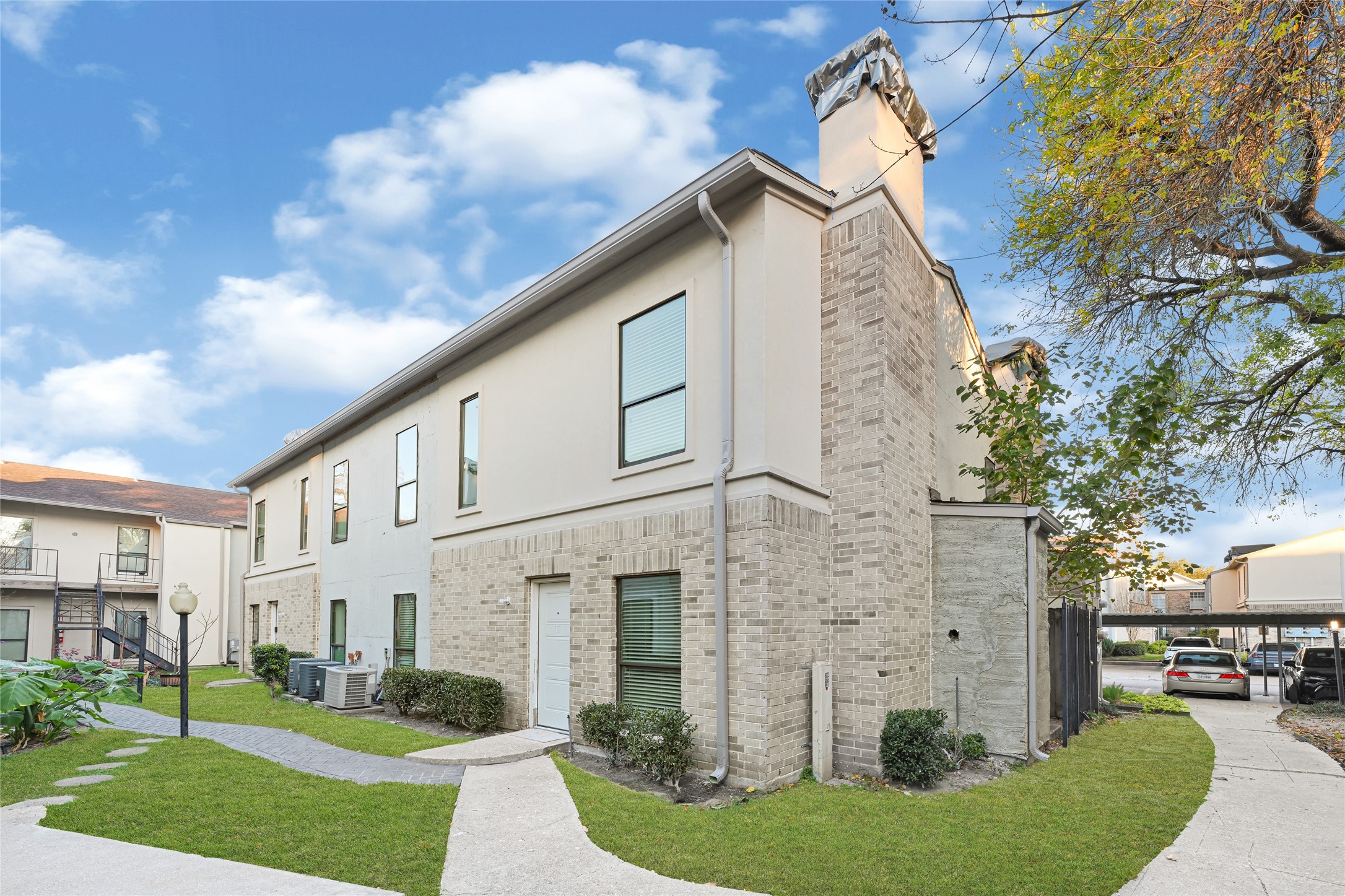 a view of a white house next to a yard with big trees