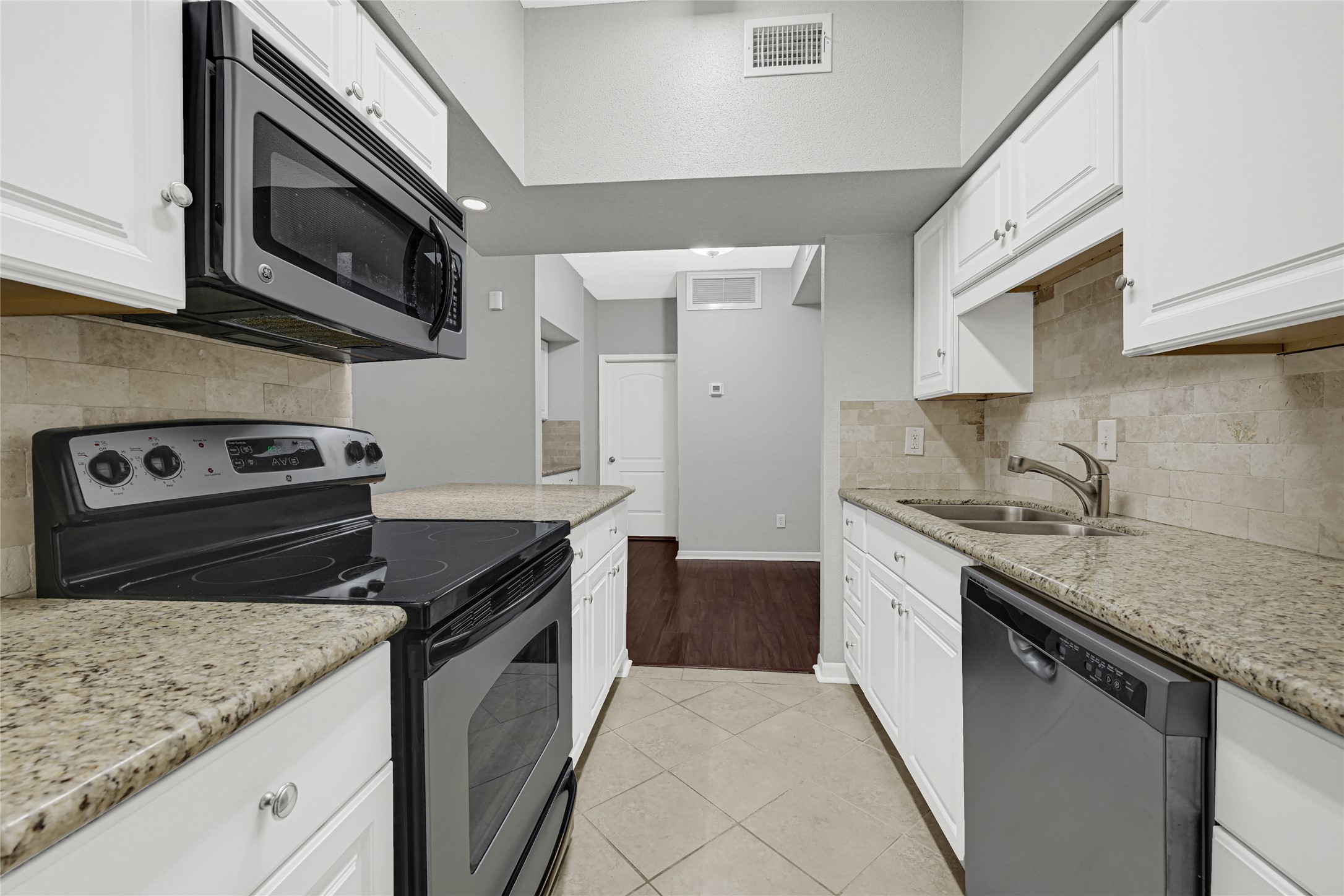 2425 Augusta Drive, Unit 29 Houston, TX 77057 - Photo 13 of 30 a kitchen with stainless steel appliances granite countertop a sink dishwasher stove and microwave with wooden cabinets