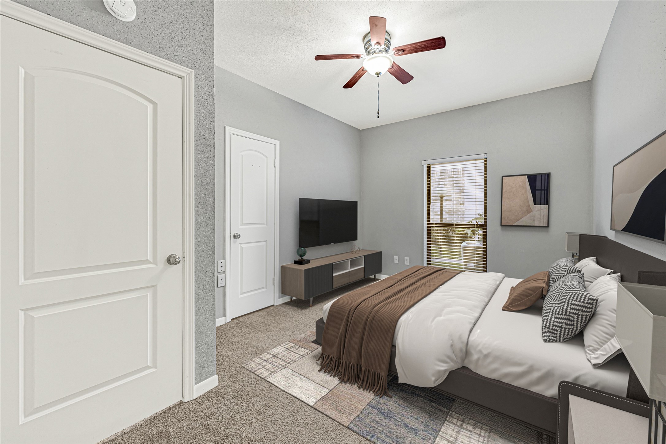 2425 Augusta Drive, Unit 29 Houston, TX 77057 - Photo 14 of 30 This first floor bedroom is spacious with neutral gray walls and carpeted flooring. It features two windows with blinds, providing natural light, and a ceiling fan for comfort. The room's clean and modern design offers a versatile space suitable for various uses.