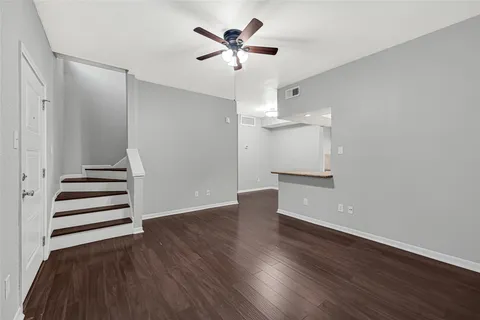 an empty room with wooden floor and a ceiling fan