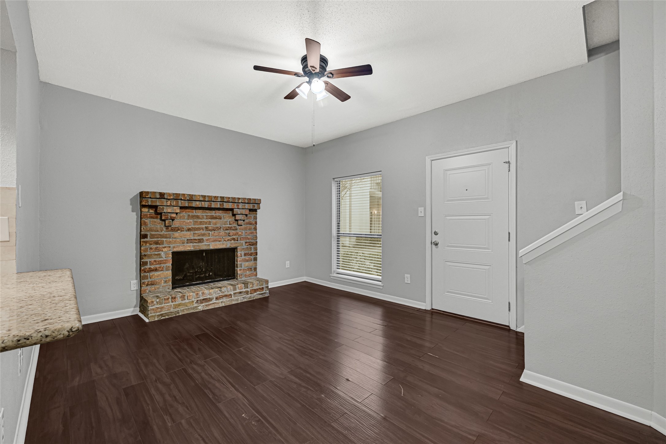 2425 Augusta Drive, Unit 29 Houston, TX 77057 - Photo 4 of 23 an empty room with wooden floor a ceiling fan a fireplace and windows