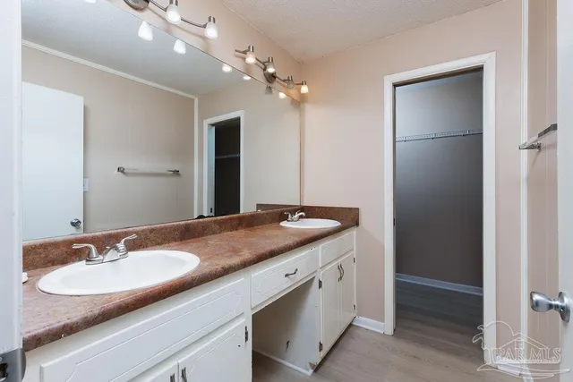 a bathroom with a granite countertop sink a light fixture and a mirror