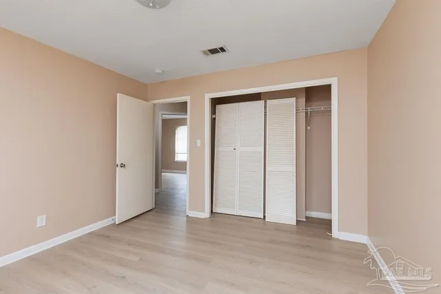 a view of an empty room with wooden floor and closet