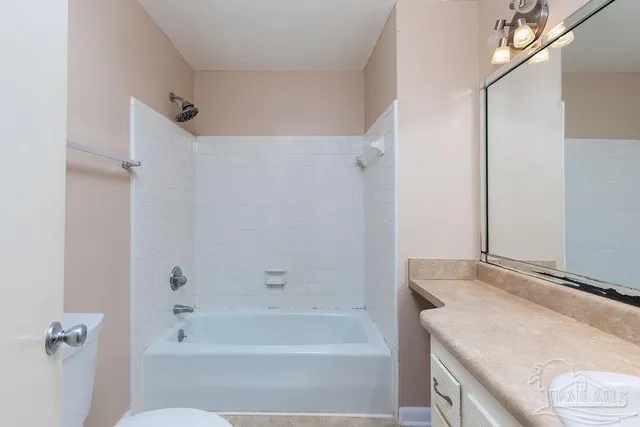 a bathroom with a granite countertop sink a toilet and shower