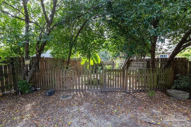 a view of a backyard with large trees and wooden fence