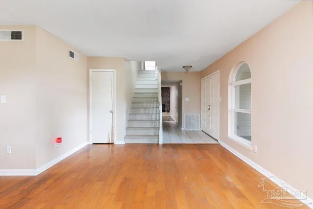 a view of an empty room with wooden floor and entryway