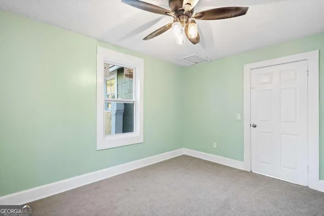 an empty room with a window and a fan
