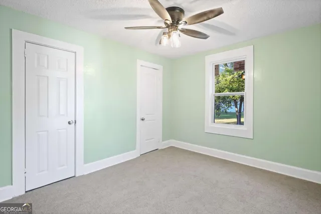 an empty room with windows and fan