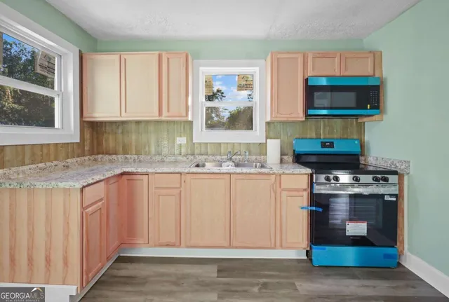 a kitchen with stainless steel appliances granite countertop a stove a sink and a microwave