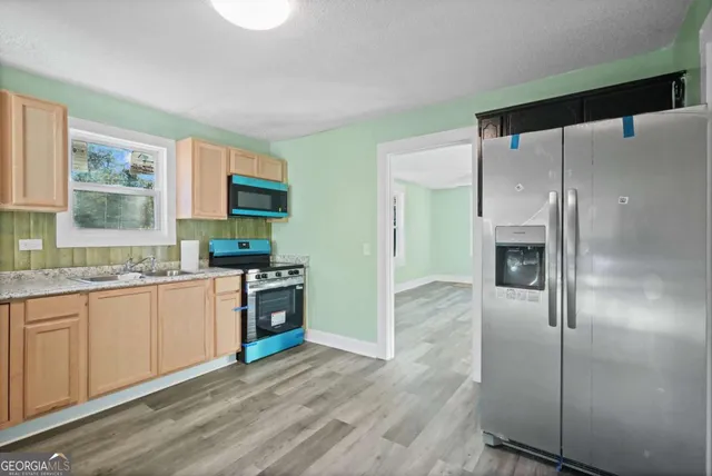 a kitchen with stainless steel appliances granite countertop a refrigerator a sink and a stove