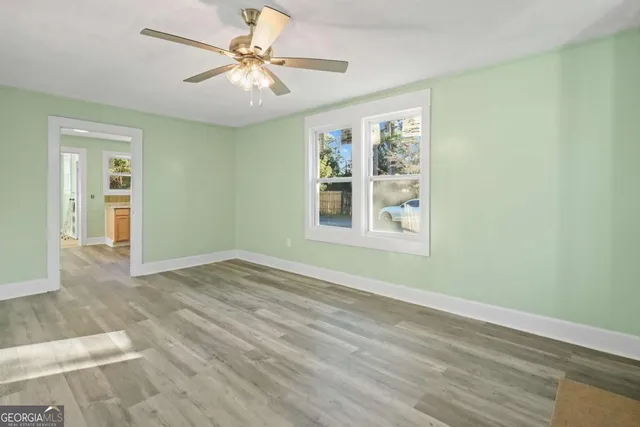 a view of an empty room with window and a chandelier fan