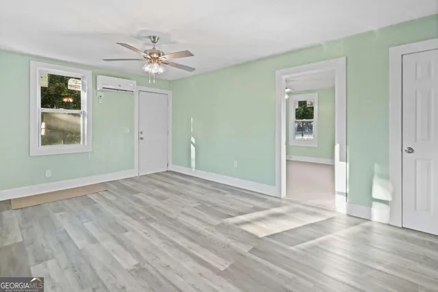 a view of an empty room with wooden floor and a window
