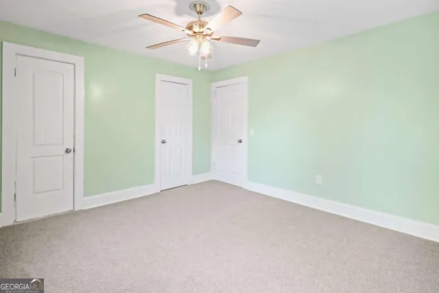an empty room with a ceiling fan and a window