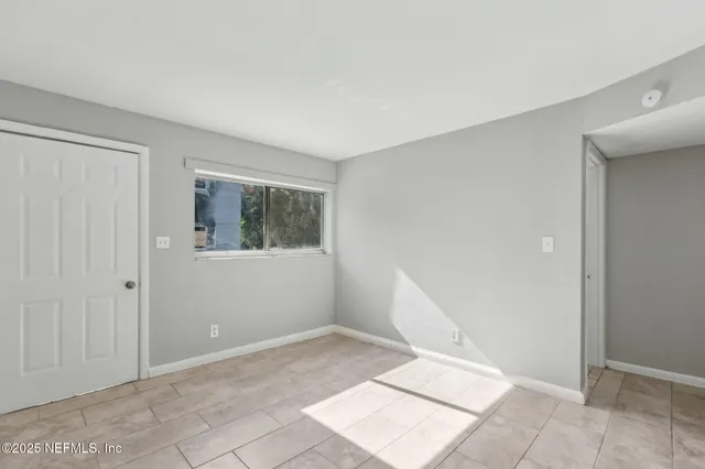 a view of an empty room with window and stairs
