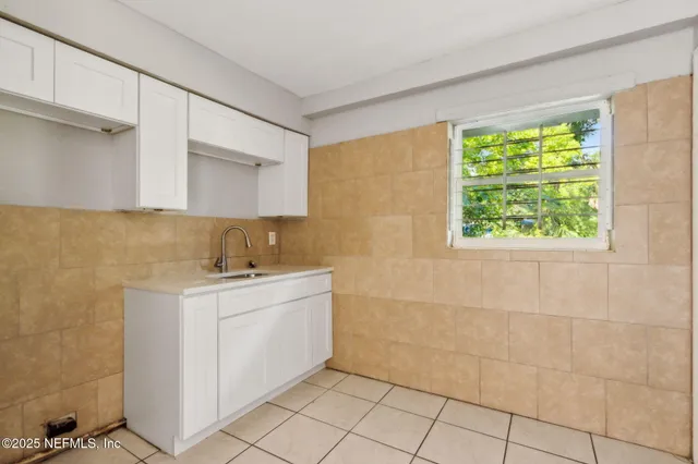 a utility room with a sink a cabinetry and a window