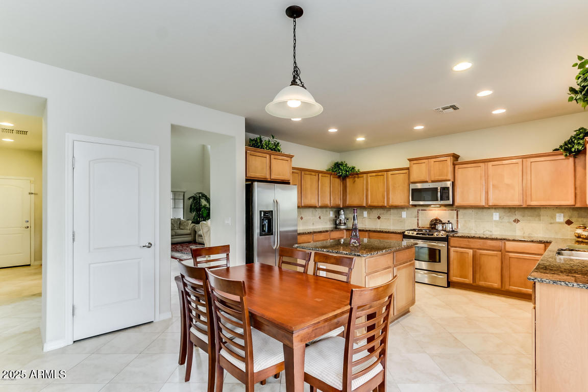 1827 West Black Hill Road Phoenix, AZ 85085 - Photo 14 of 49 a kitchen with stainless steel appliances kitchen island granite countertop a sink a stove a refrigerator cabinets and chairs