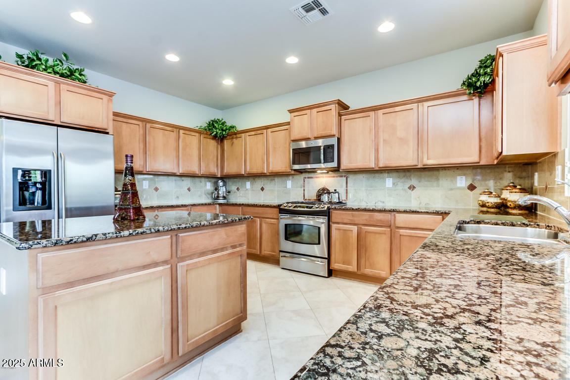 1827 West Black Hill Road Phoenix, AZ 85085 - Photo 18 of 49 a kitchen with kitchen island granite countertop a stove sink and cabinets