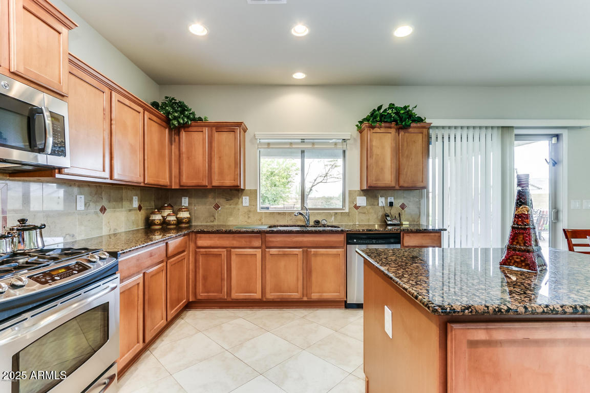 1827 West Black Hill Road Phoenix, AZ 85085 - Photo 25 of 49 a kitchen with stainless steel appliances granite countertop a stove sink and cabinets