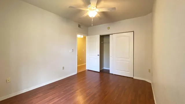 an empty room with wooden floor and a ceiling fan