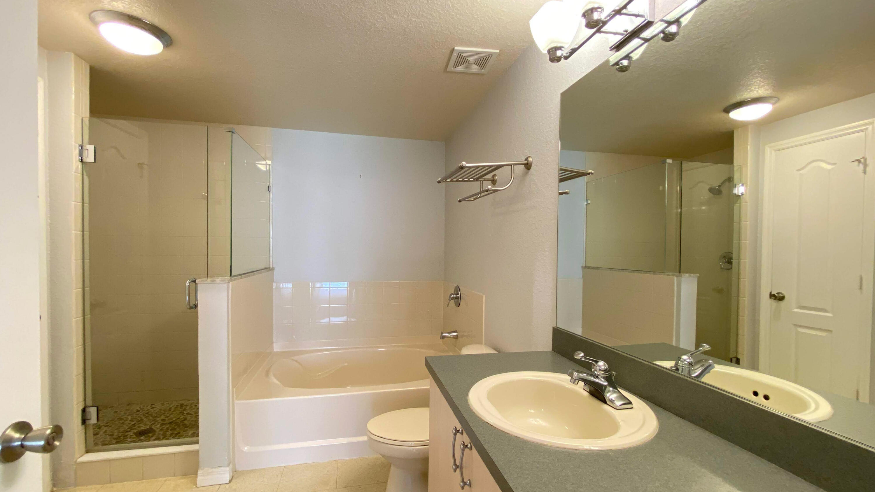 118 Southwest Peacock Boulevard, Unit 101 Port St. Lucie, FL 34986 - Photo 10 of 38 a bathroom with a granite countertop sink a toilet a mirror and shower