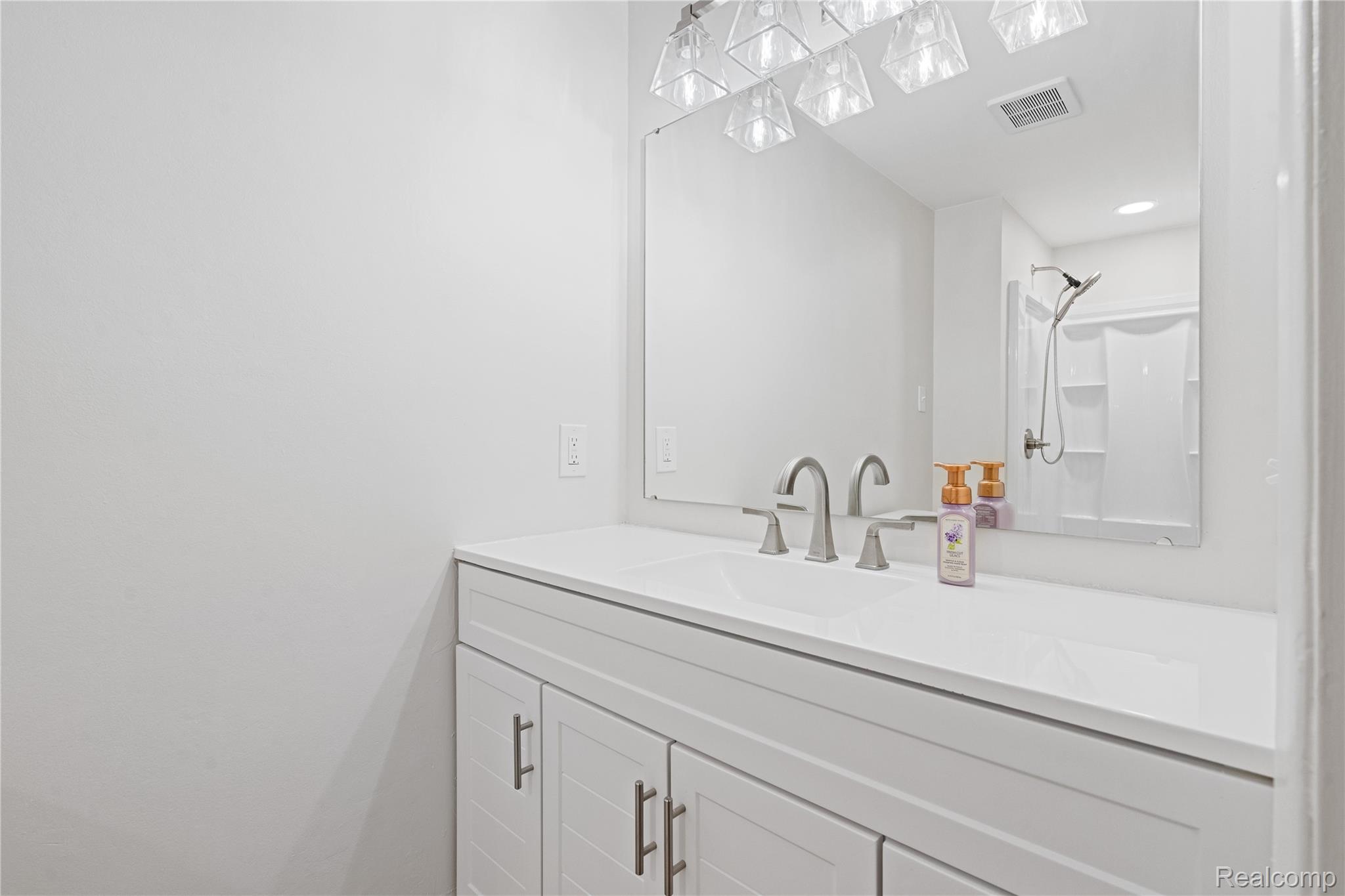 8240 Hampton Road Grosse Ile, MI 48138 - Photo 20 of 33 Vanity with an integrated sink, brushed nickel faucet, large mirror, and white shaker-style cabinetry