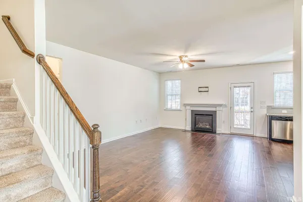a view of an empty room with wooden floor fireplace and a window