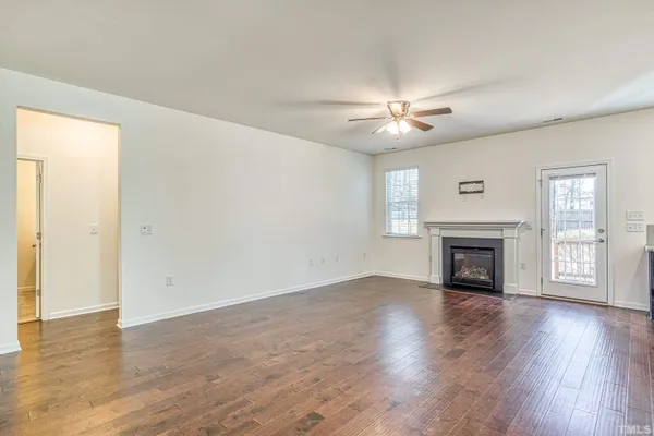 an empty room with windows a fireplace and wooden floor