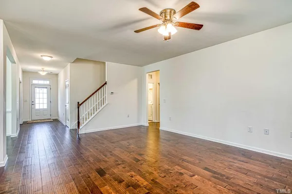 an empty room with wooden floor fan and windows