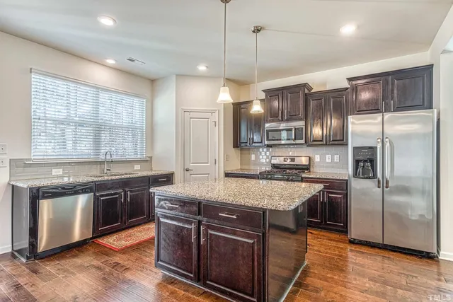a kitchen with stainless steel appliances granite countertop a stove a sink a refrigerator and a center island